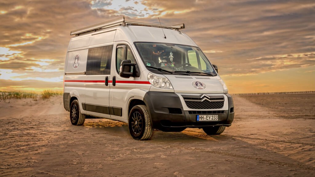 Arty Vans Jumper/ Ducato Camper in Totale von vorne am Strand im Sonnenuntergang