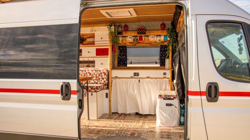 Blick durch die Schiebetür in einen Arty Van Innenausbau. Warme Farben, Eichenholz, Bambusrohre, Akustikpaneele, Terrakotta Vintage Boden.