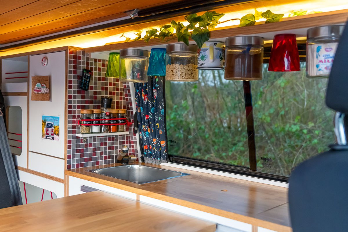 Arty Vans Creations VW T6 Camper Innenraum. - Küchenzeile mit Eichenholz, warmen Farben, 3D-Fliesen, Gläser, Designvorhängen usw.