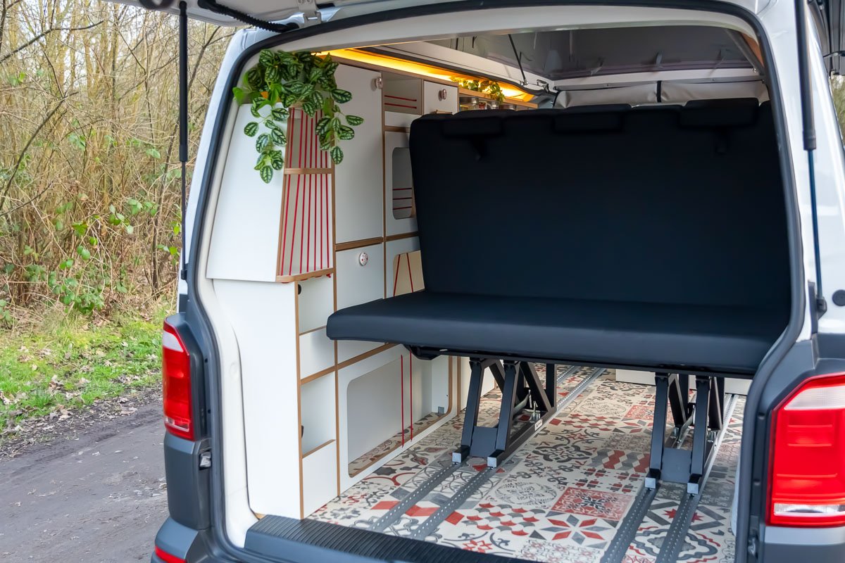 Arty Vans Creations VW T6 Camper Innenraum - Geöffnete Heckklappe mit Blick in den Van. Schlafsitzbank, Möbelzeile und Vintage Terrakotta PVC Boden.